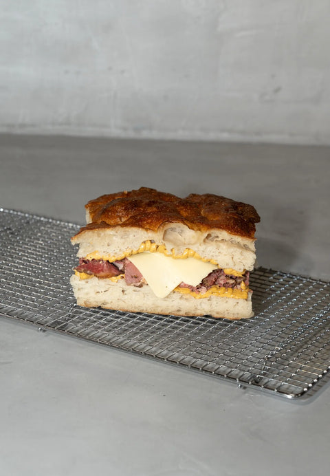 Focaccia sandwich de masa madre de pastrami, salsa holandesa y queso gouda